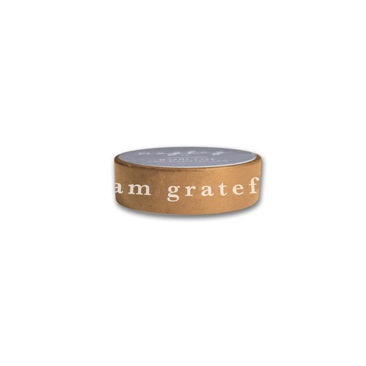 The "I Am Grateful Washi Tape - Gold Yellow" by Maylay Co. captures the elegant charm of decorative washi tapes with its gold-yellow design, reminiscent of a brown cylindrical candle holder that has "I am grateful" elegantly printed in white. Its design's simplicity is accentuated against a plain white background, hiding the top and enhancing its serene beauty.
